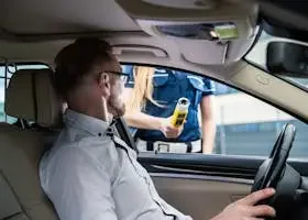 Officer administering a breathalyzer test to a driver during a roadside check for safety.