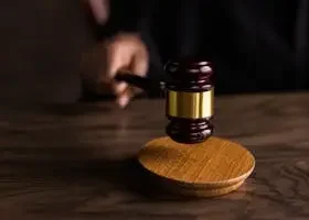 A gavel striking a sound block, symbolizing justice and legal authority in a courtroom setting.